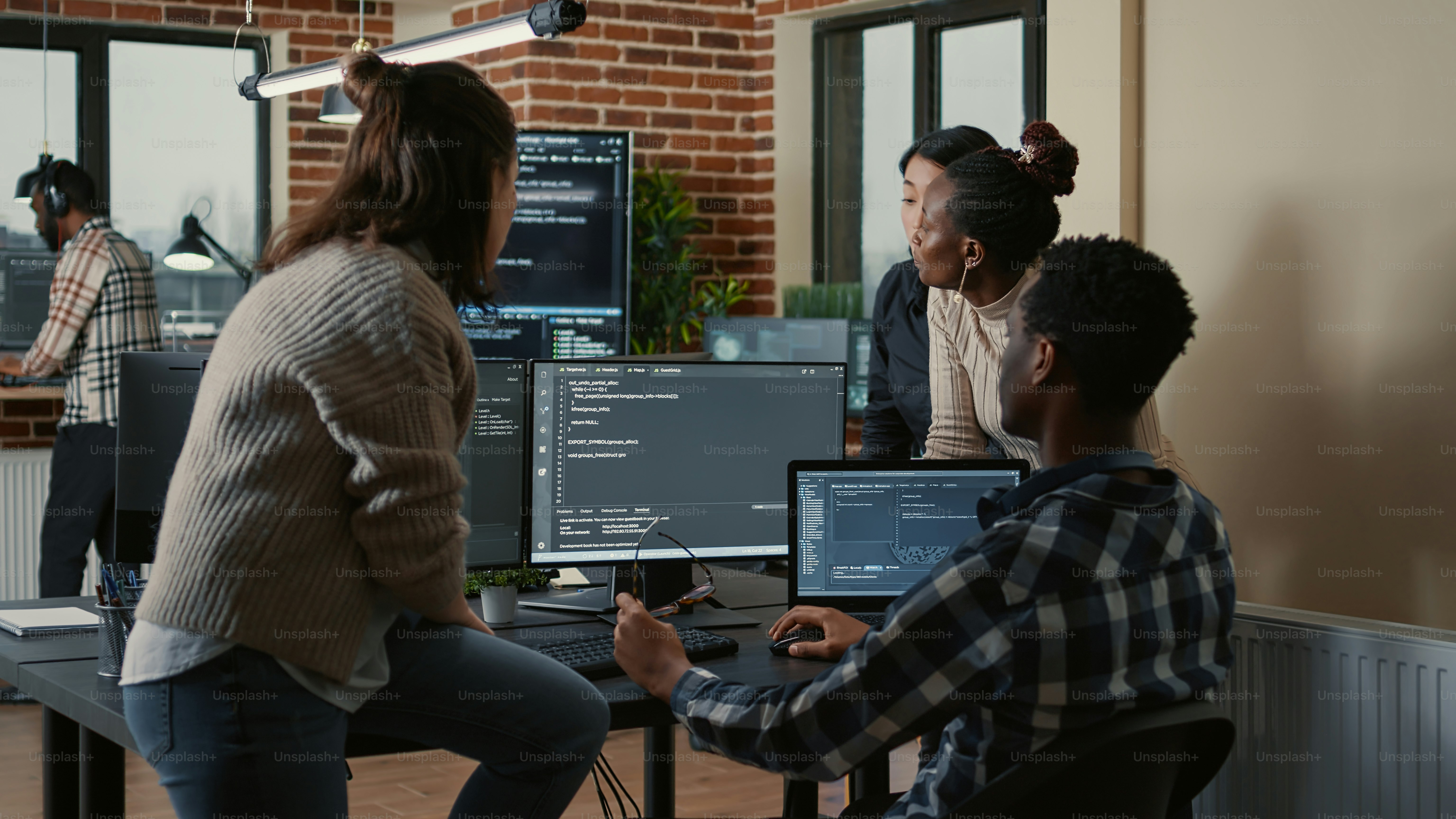 A group of people working on computer code in a modern office workspace